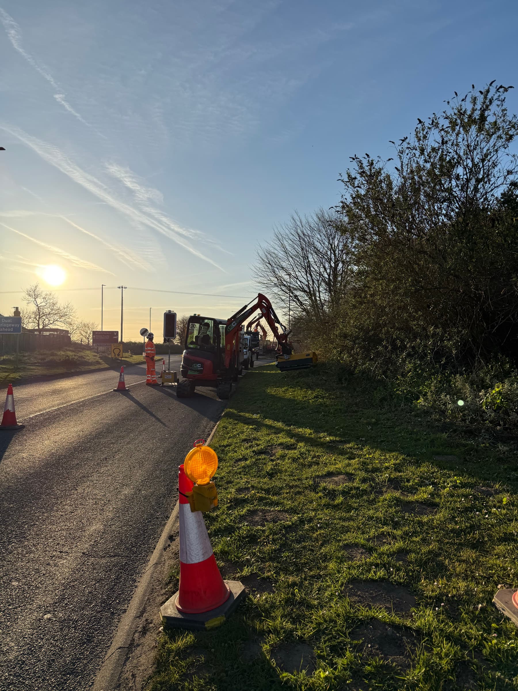 A GroundCore excavator clearing a roadside hedge and boundary at sunrise in Caister