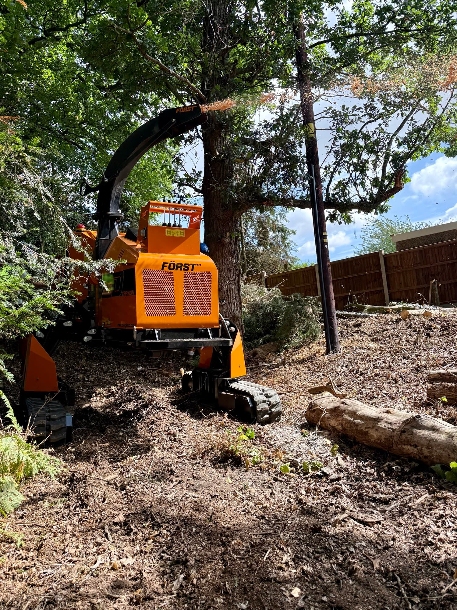A wood chipper processing cleared branches and scrub